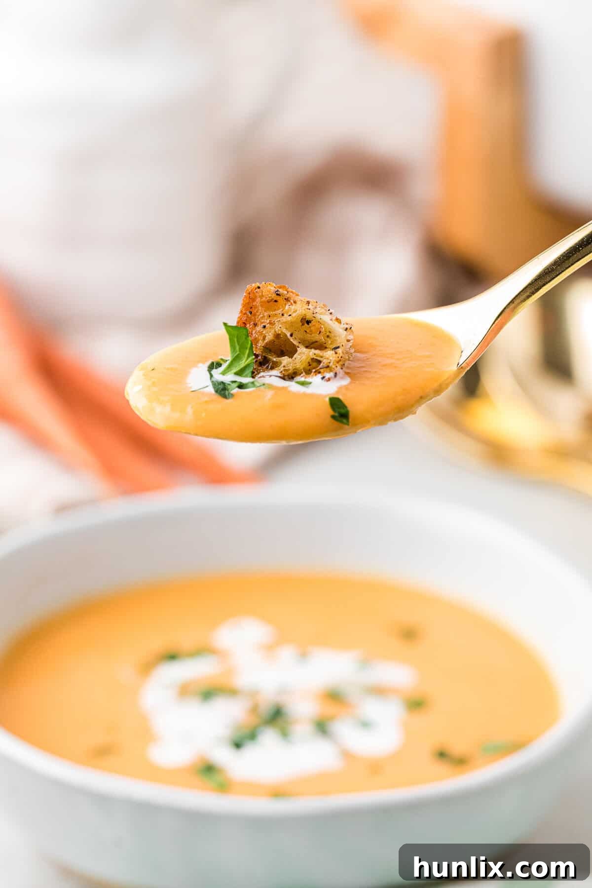 A golden spoon showcasing the creamy, smooth texture of the carrot soup.