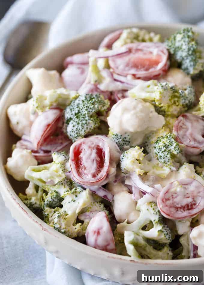 Yuletide Medley Salad 3 Close-up of creamy Christmas Salad with broccoli, cauliflower, red onion, and halved cherry tomatoes.
