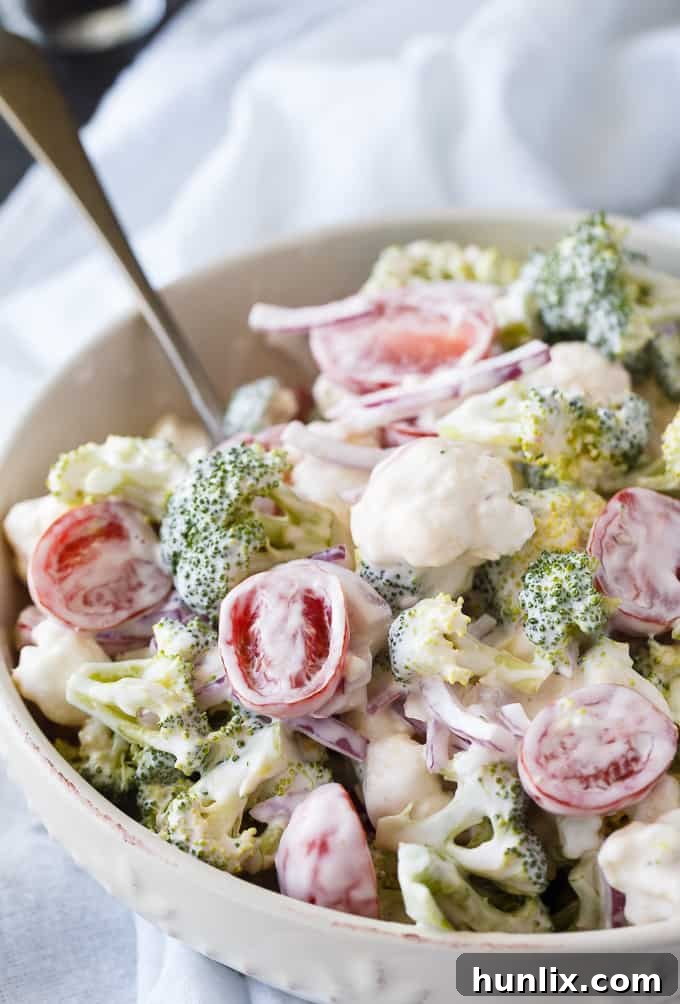 Yuletide Medley Salad 5 Ingredients for Christmas Salad, including fresh broccoli, cauliflower, red onion, cherry tomatoes, and a bowl of creamy dressing.