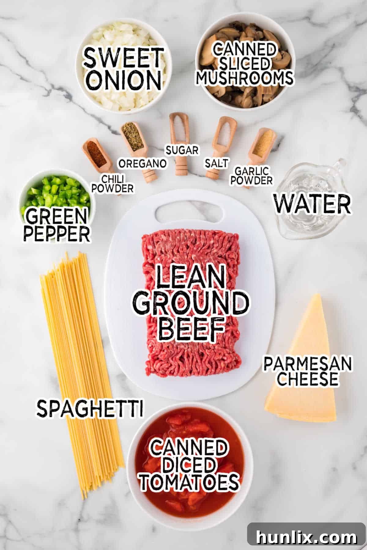 Easy Skillet Spaghetti 3 Various ingredients laid out to make one-pan spaghetti, including ground beef, diced tomatoes, spaghetti noodles, onions, and spices.