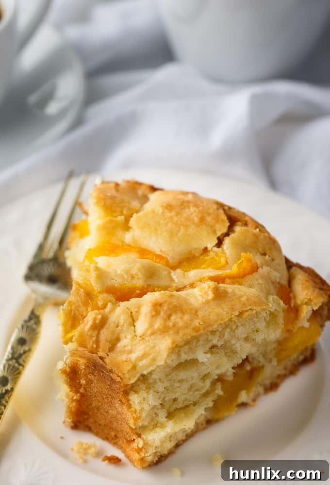 Moist Peach Coffee Cake, generously dusted with powdered sugar, ready to be served for breakfast or dessert