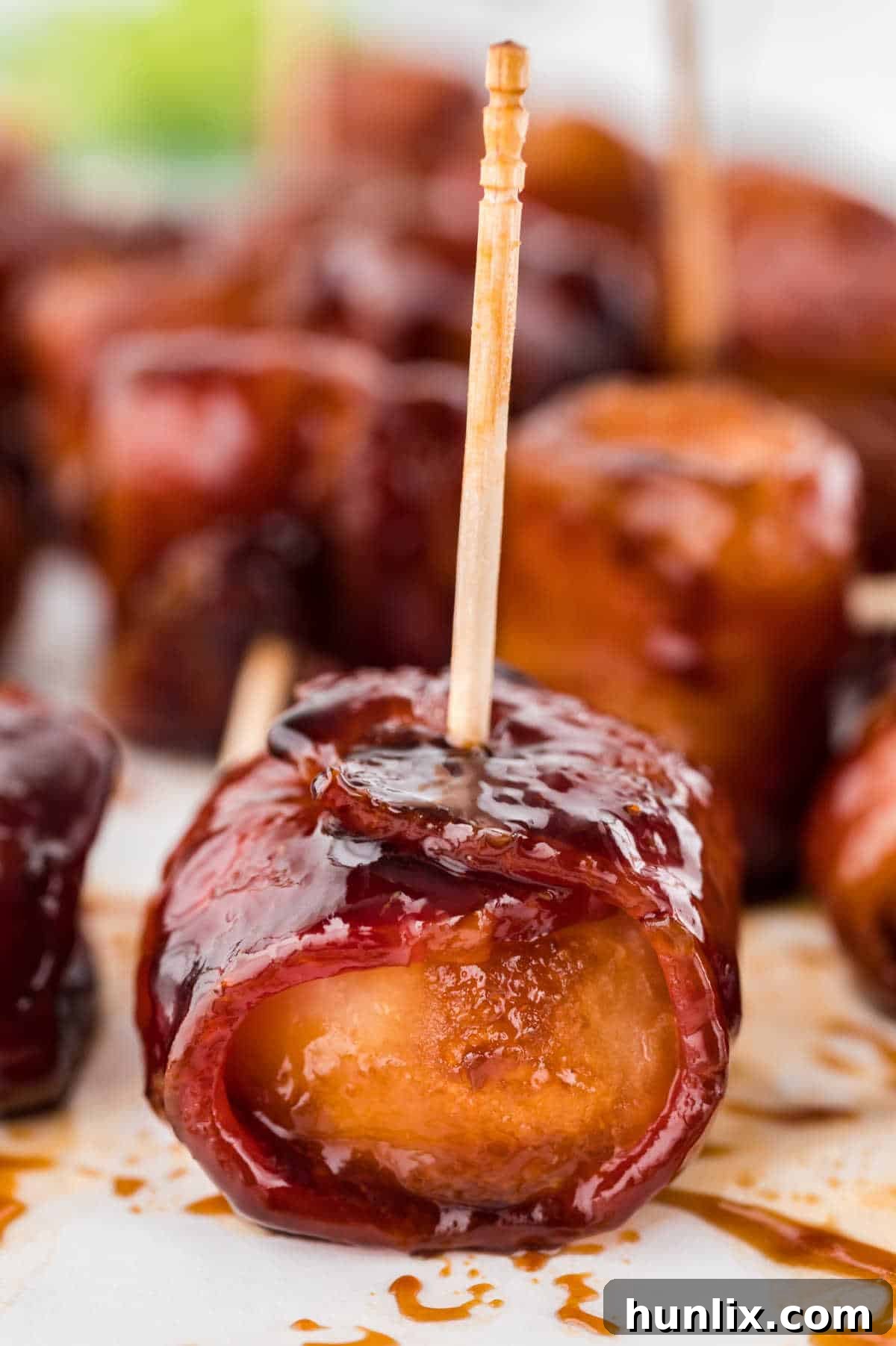 A single bacon wrapped water chestnut, perfectly glazed and secured with a toothpick, ready for tasting.