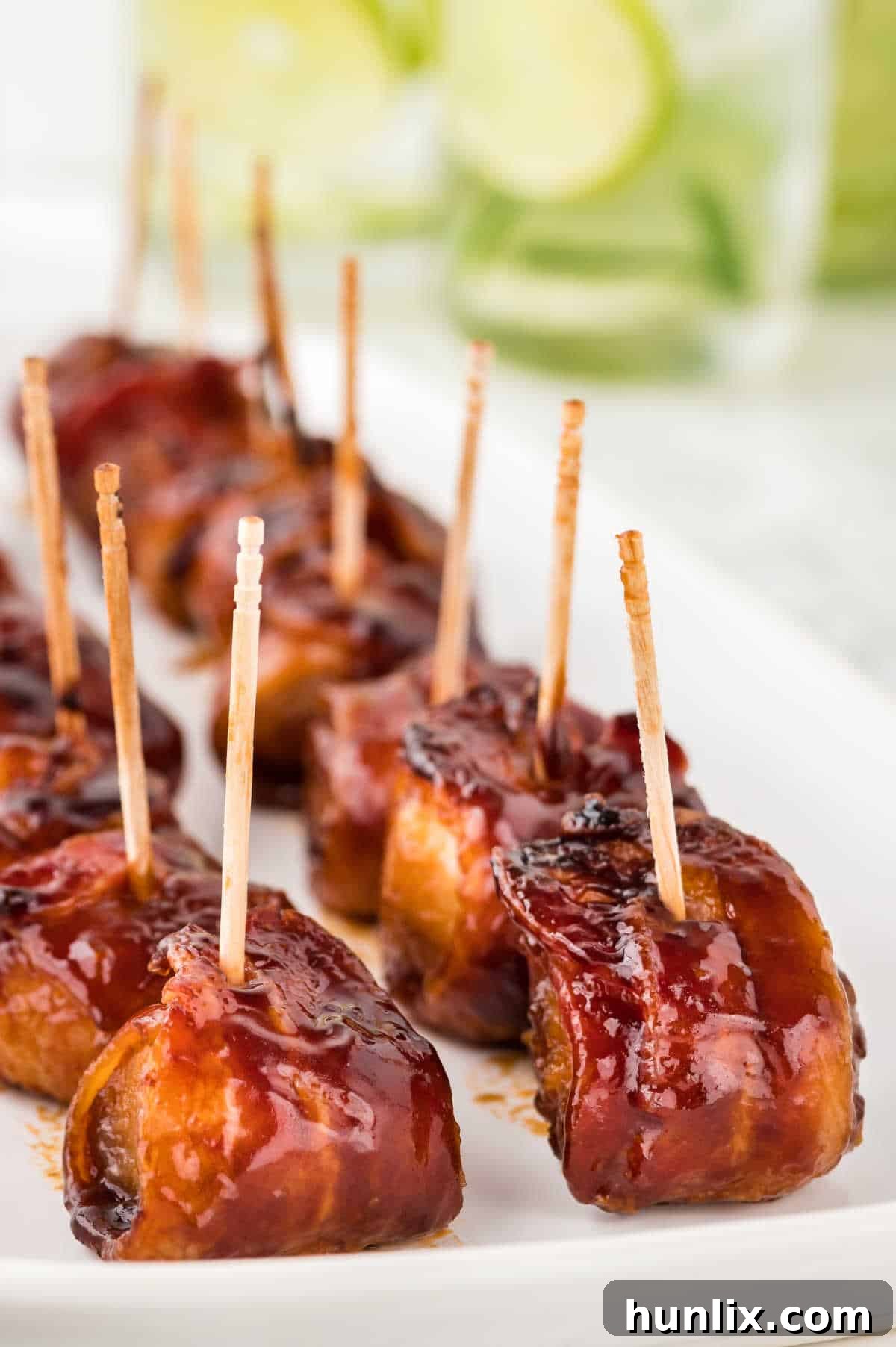 A generous pile of freshly baked bacon wrapped water chestnuts on a platter, highlighting their golden-brown color and irresistible glaze.
