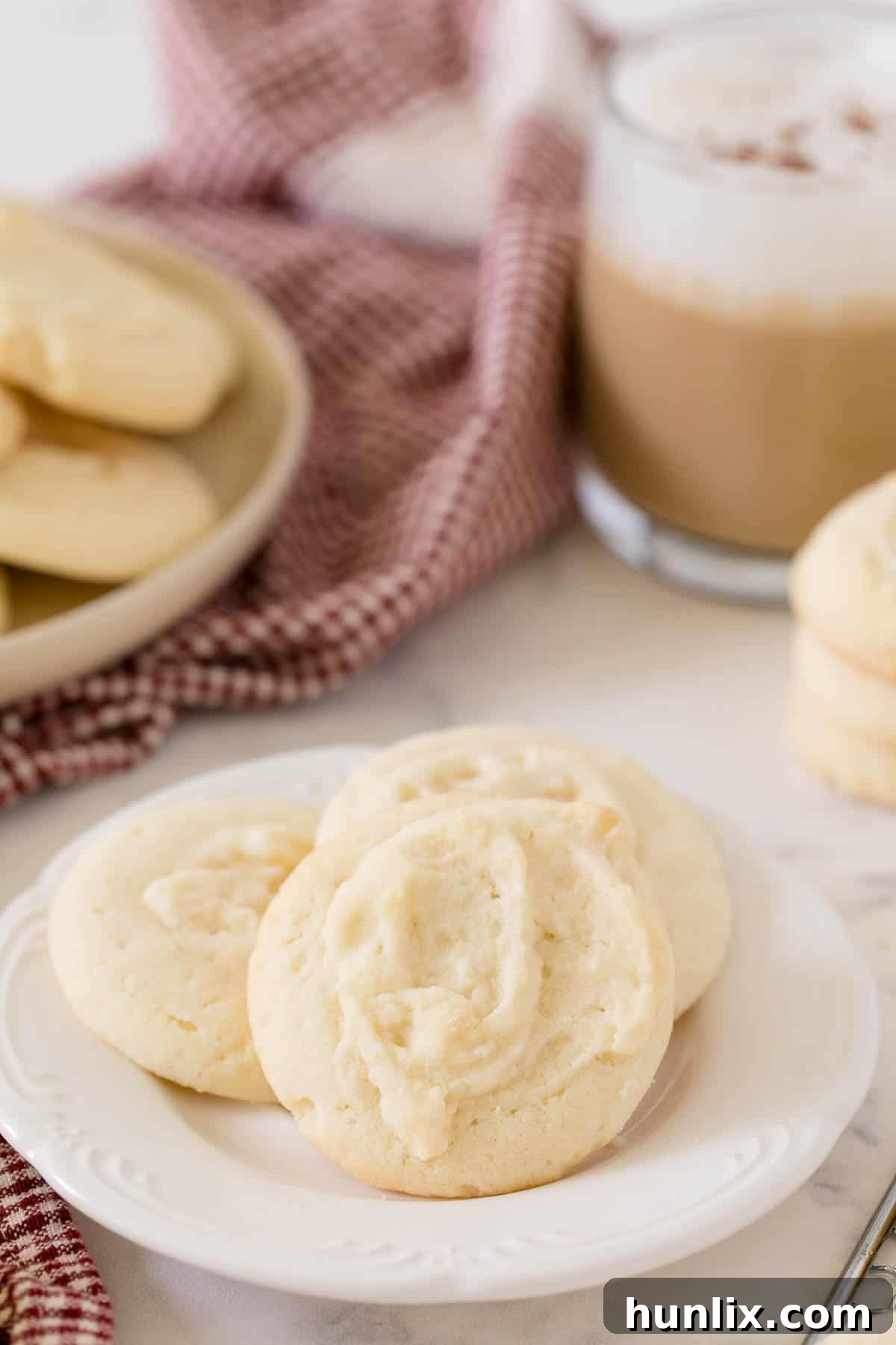 Three perfectly baked whipped shortbread cookies arranged delicately on a white plate.