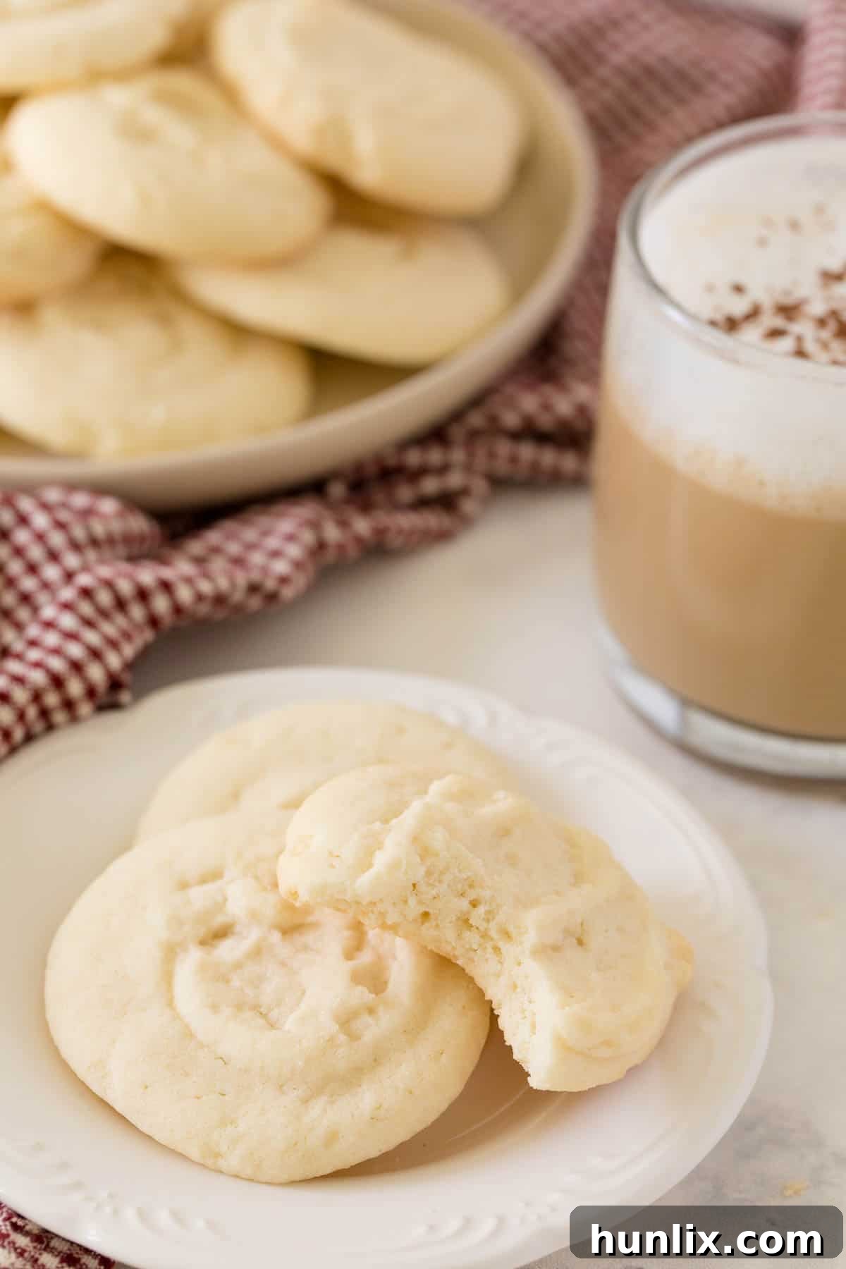 A plate of whipped shortbread cookies, with one cookie showing a delicate bite taken out, revealing its tender interior.