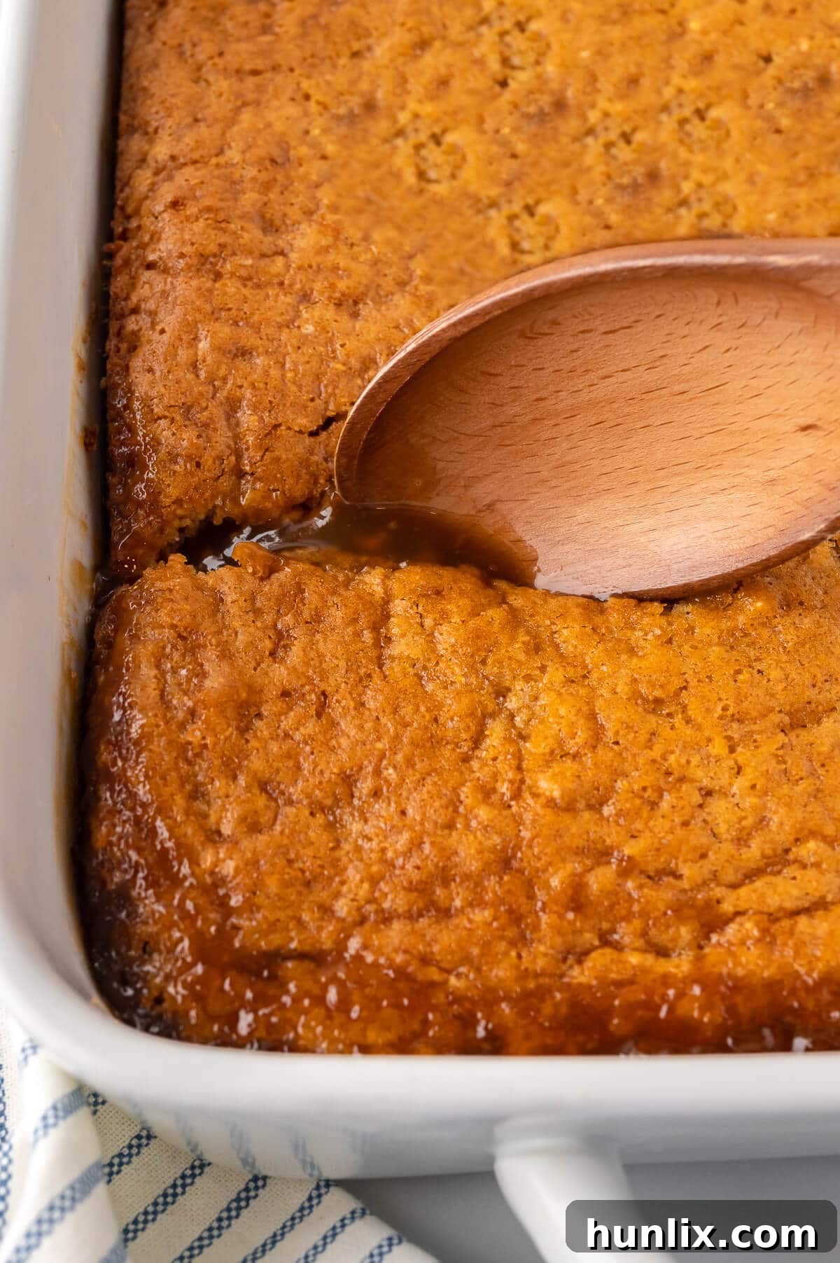 Half-Hour Pudding in a baking pan, ready to be served, with a wooden spoon.