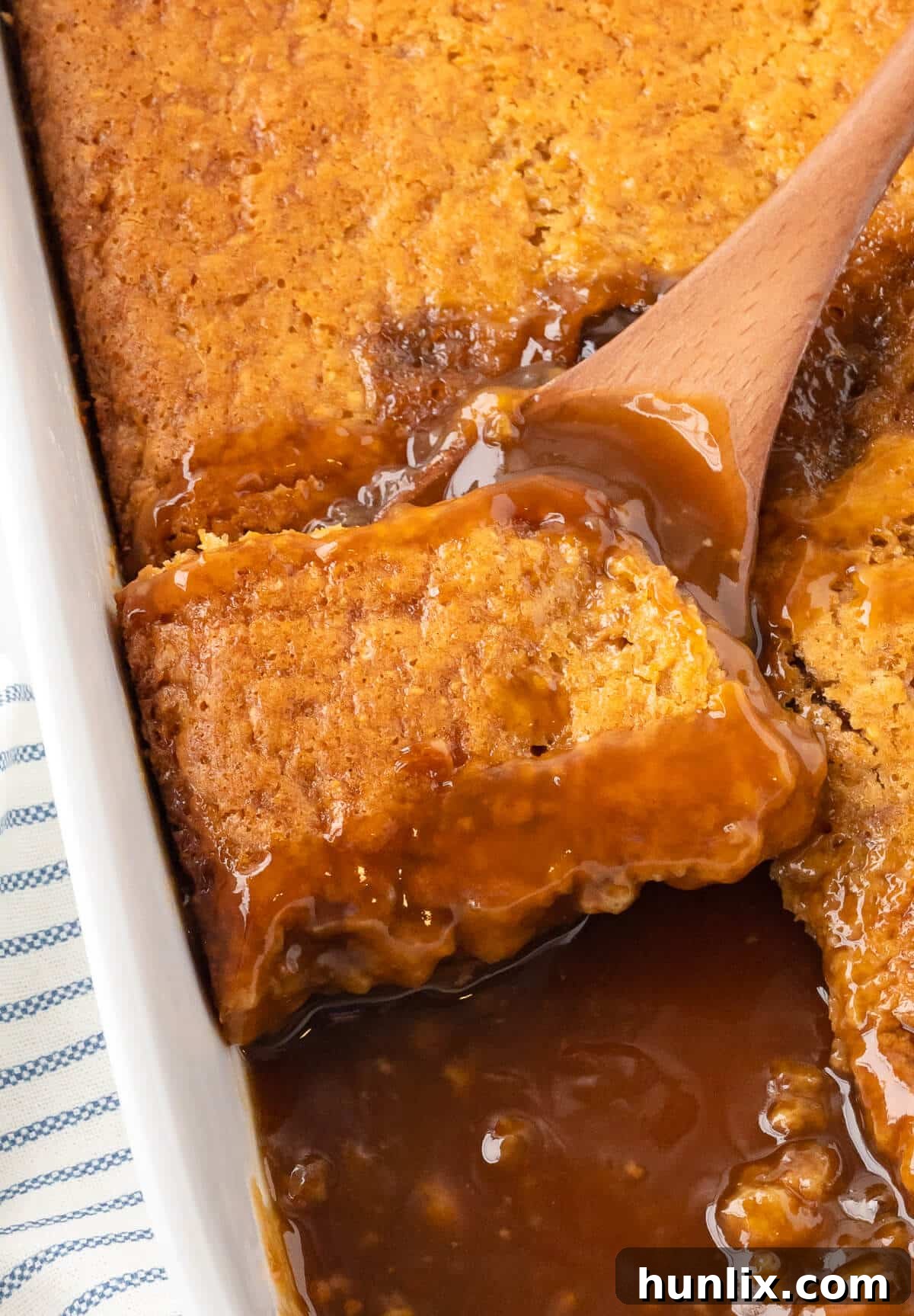 Freshly baked Half-Hour Pudding in a pan, still bubbling, with a wooden spoon for serving.