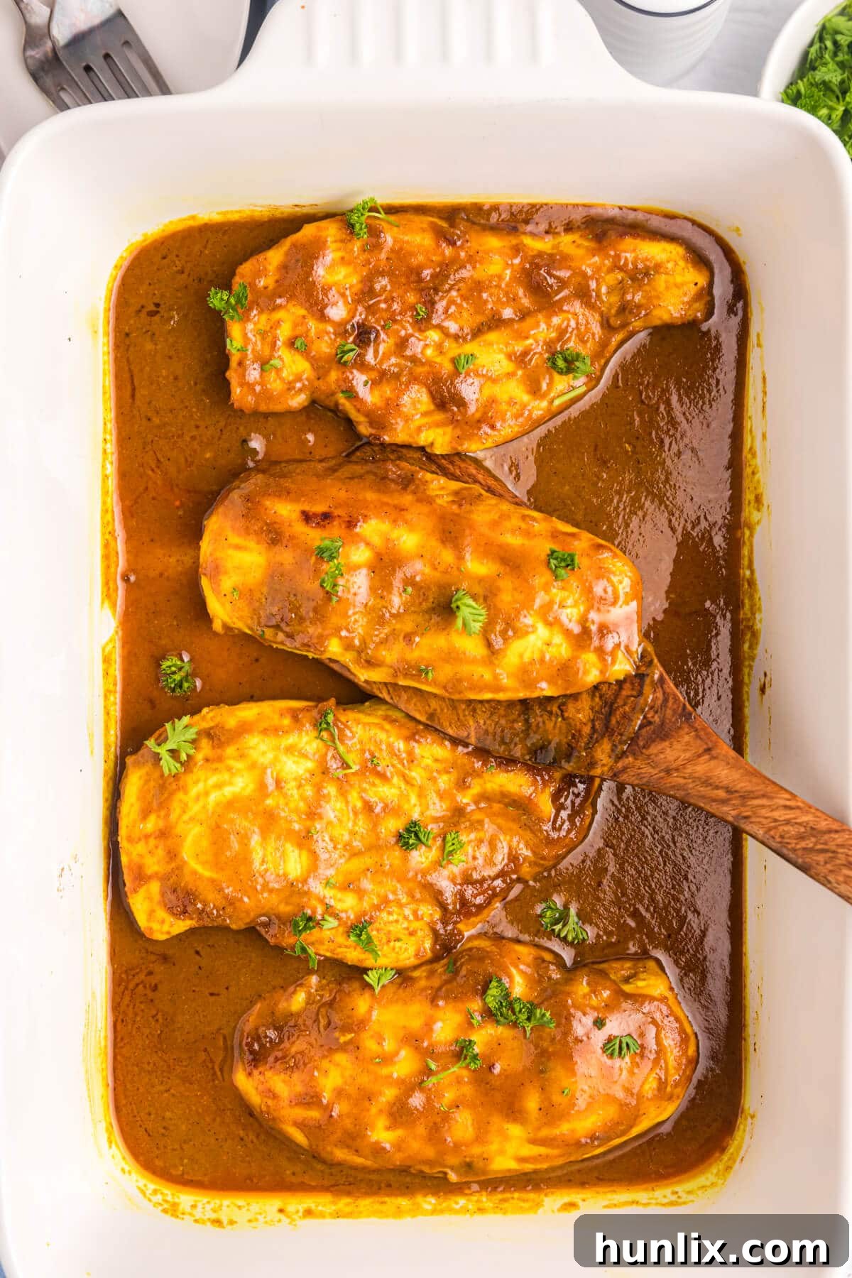 Golden brown Honey Curried Chicken served in a casserole dish, garnished with fresh parsley.