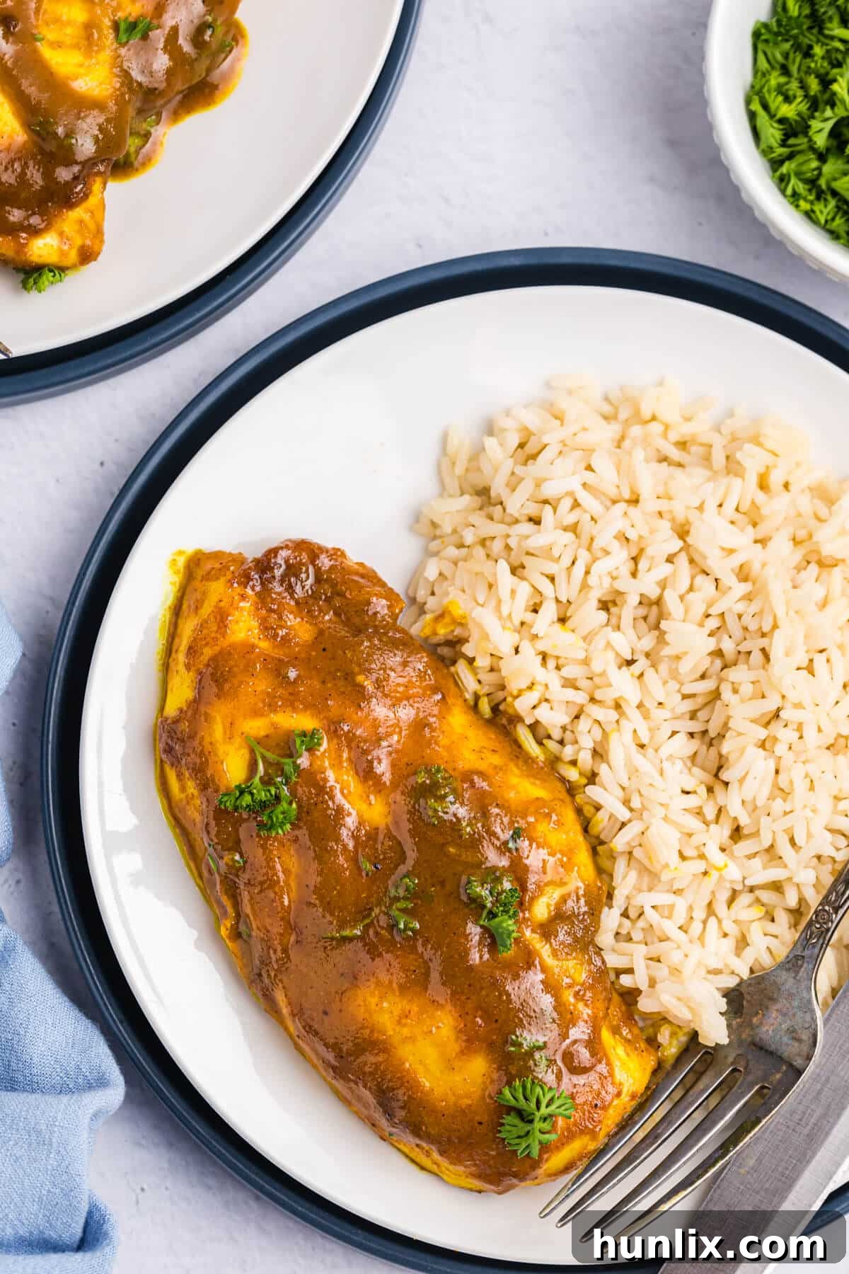 A plated serving of Honey Curried Chicken with white rice on a white dish.