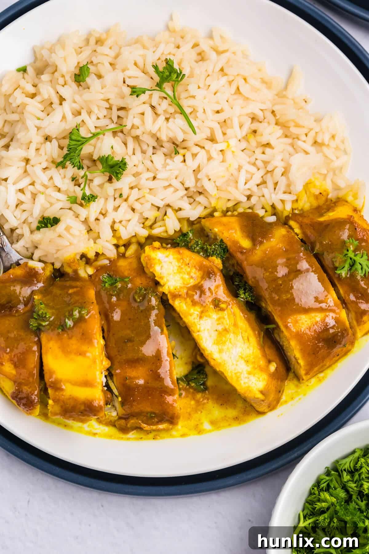 Sliced Honey Curried Chicken served on a plate with white rice, showing the tender texture.