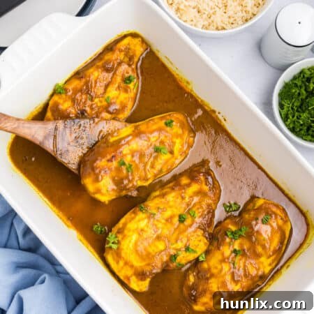 Honey curried chicken in a pan with a serving spoon.
