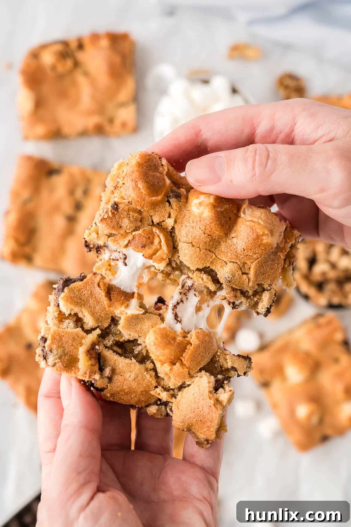 A hand breaking a Mud Hen Bar in half, revealing the gooey layers.