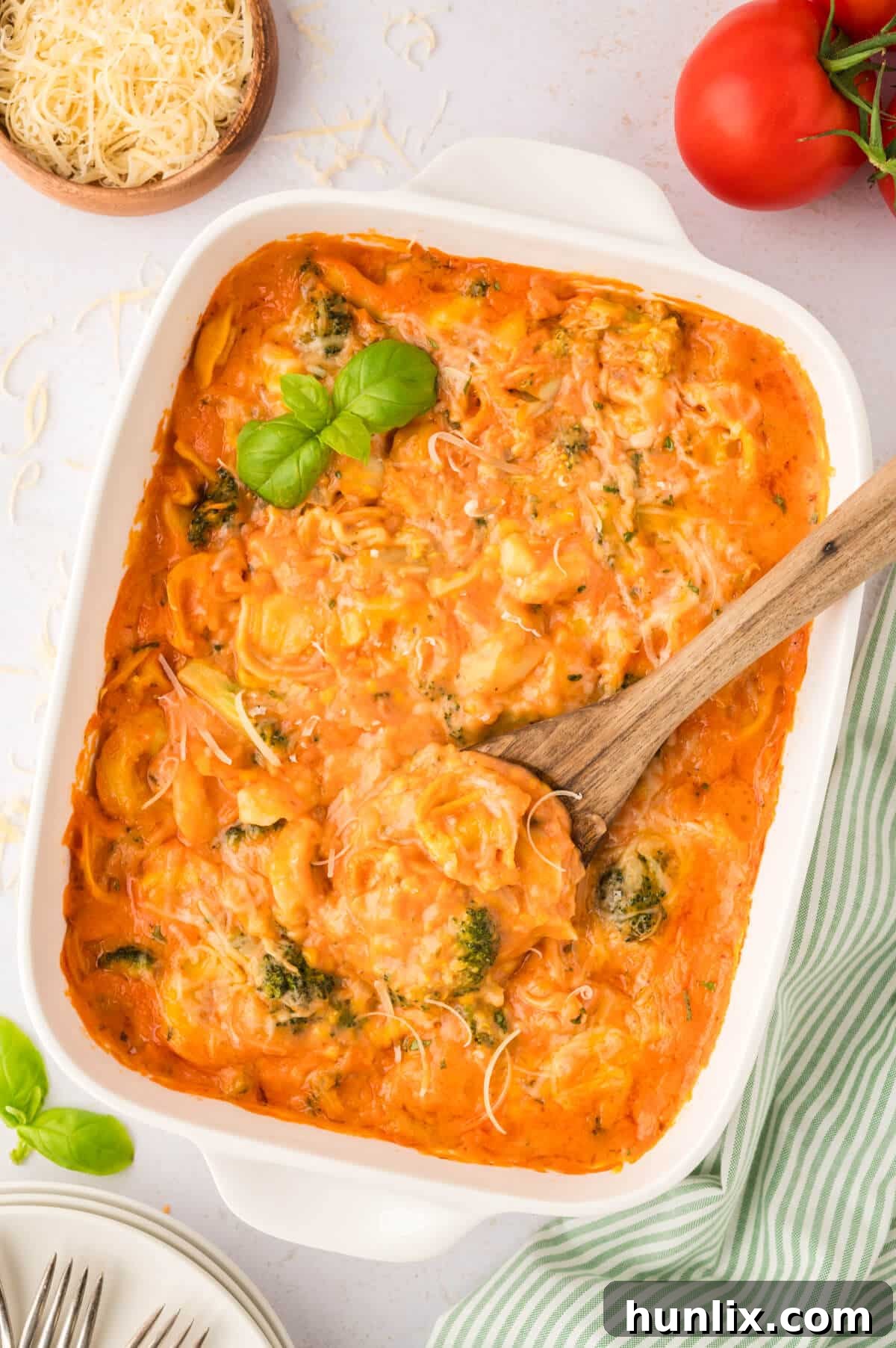 Tortellini casserole in a white casserole dish with a wooden spoon.