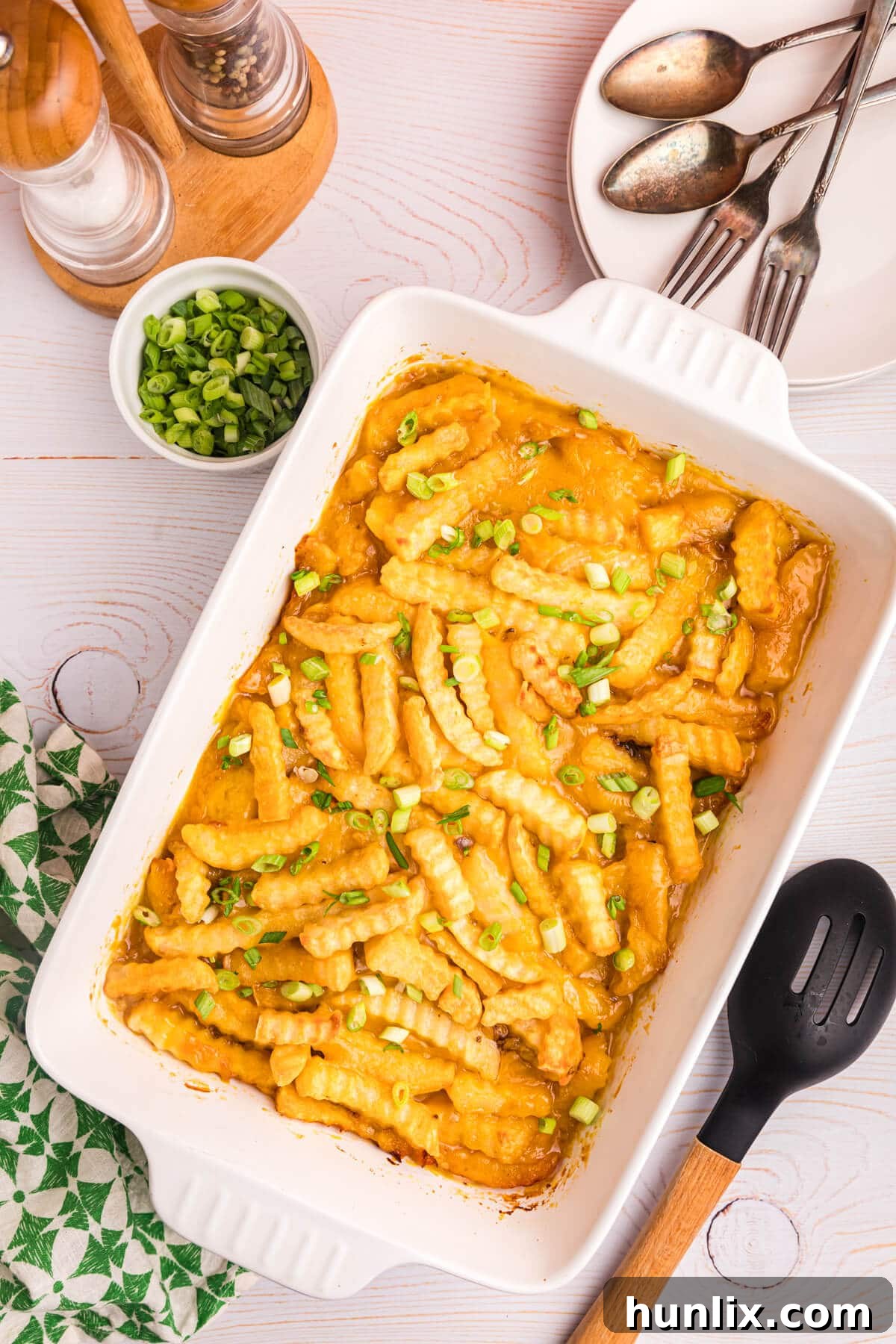 Crispy Spud Bake 2 French fry casserole in a white pan, bubbling hot and ready to serve, with a golden crust of fries.