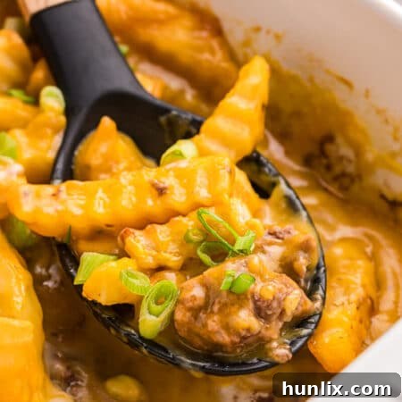 Crispy Spud Bake 9 French fry Casserole in a pan with a serving spoon.