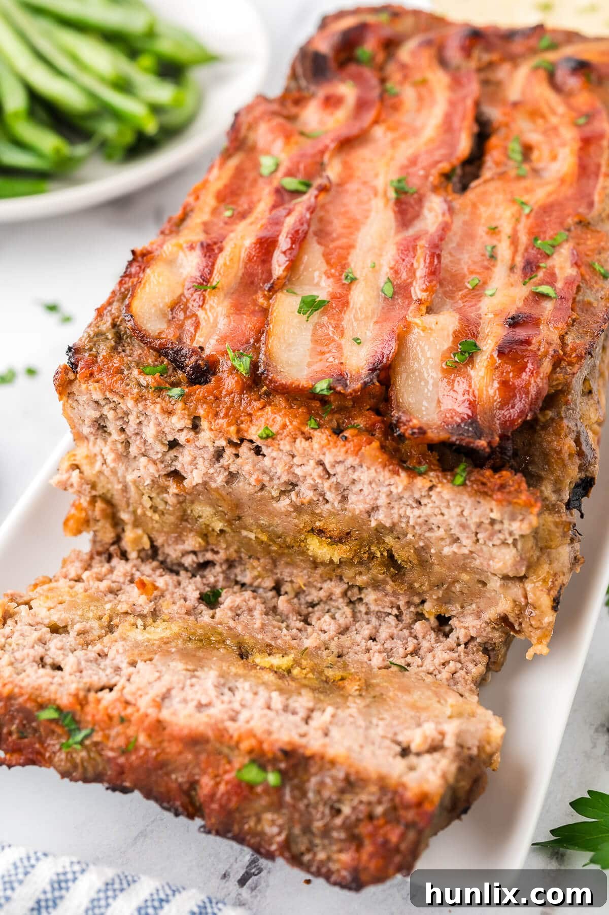 Sunday's Best Meatloaf 6 Freshly baked Sunday meatloaf on a platter with several slices cut, revealing the layers.