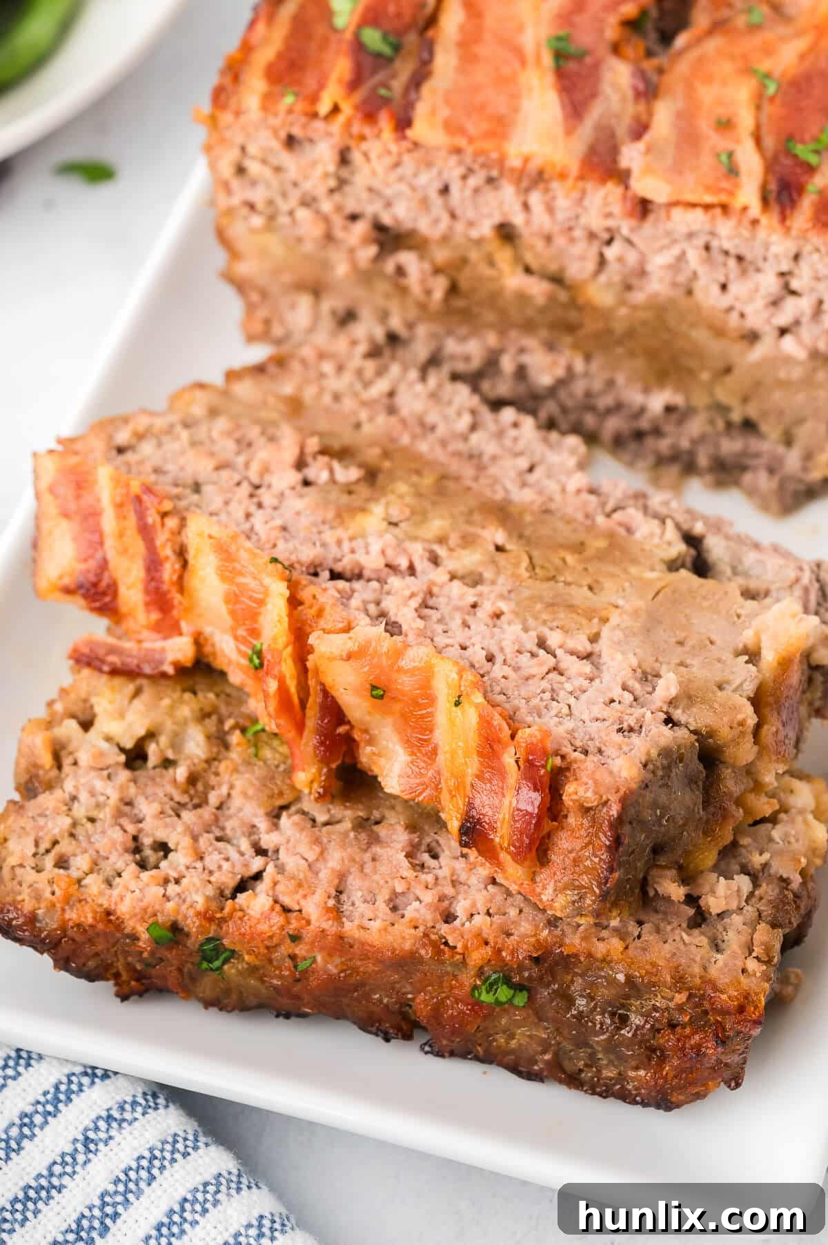 Sunday's Best Meatloaf 7 A whole Sunday meatloaf on a platter with several slices cut and removed, showcasing the stuffing layer.