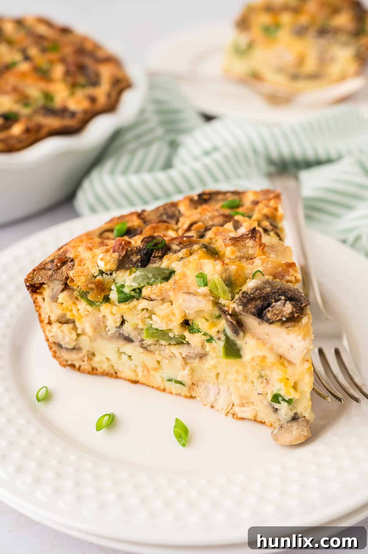 Effortless Chicken Pie 7 A perfectly sliced piece of Impossible Chicken Pie resting on a white plate, revealing its creamy filling and golden crust.