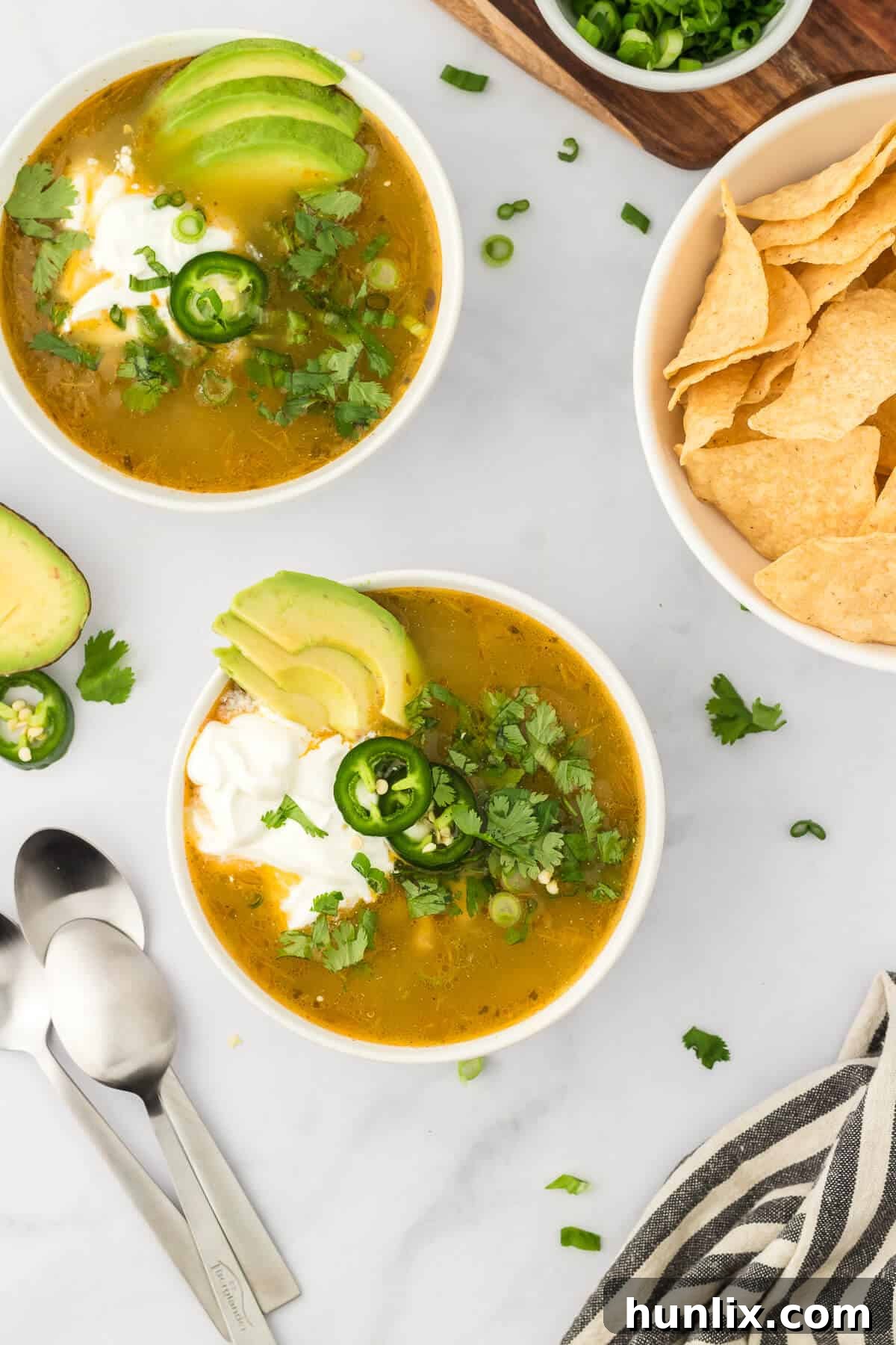 Two inviting bowls of white chicken chili, garnished and served with a side of crispy tortilla chips, perfect for dipping.