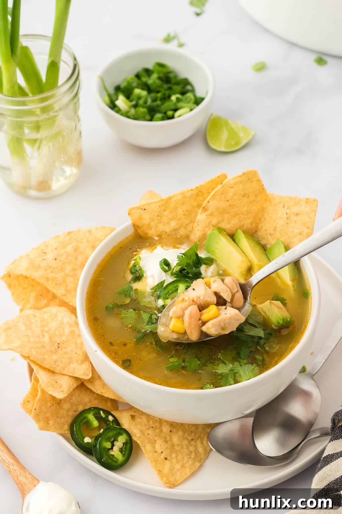 A close-up of a bowl of white chicken chili with a spoon, highlighting its creamy texture and rich ingredients.