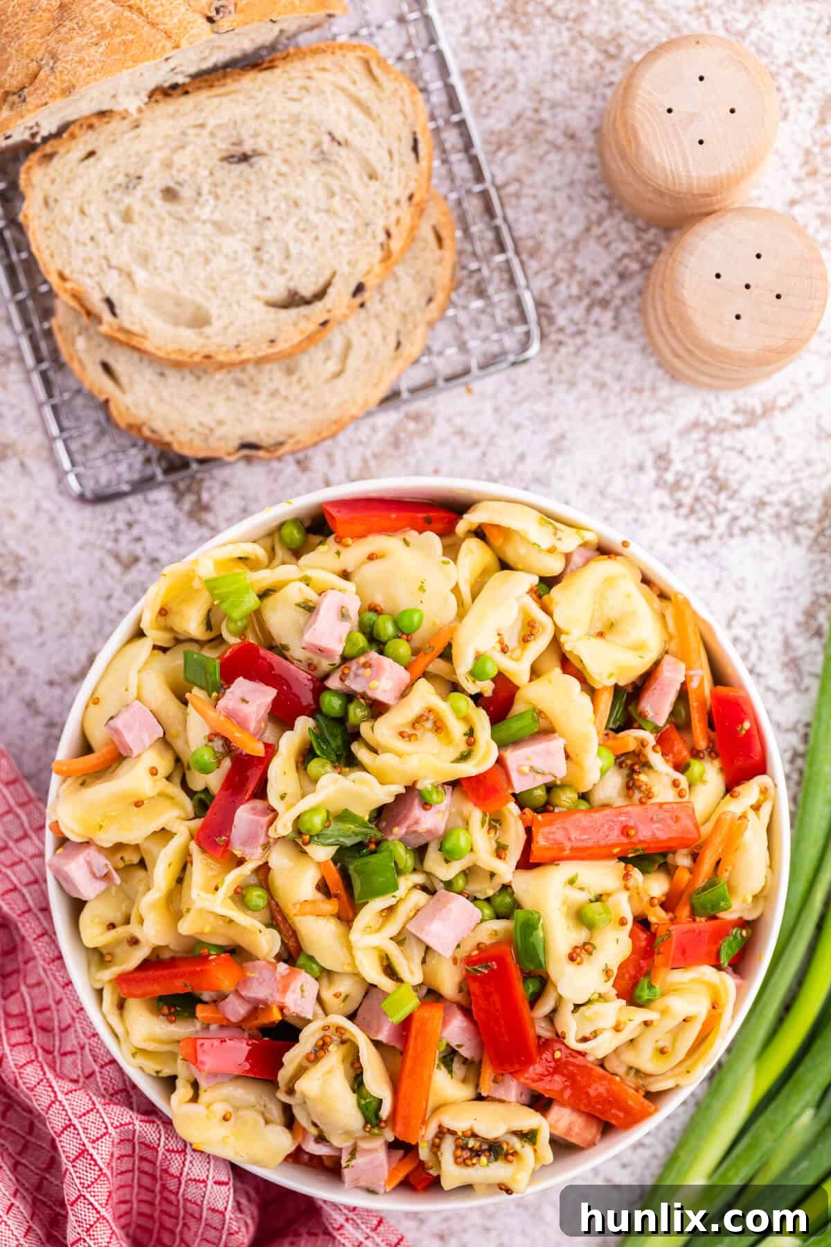 A beautifully presented tortellini salad in a white ceramic bowl, showcasing its vibrant colors and fresh ingredients.