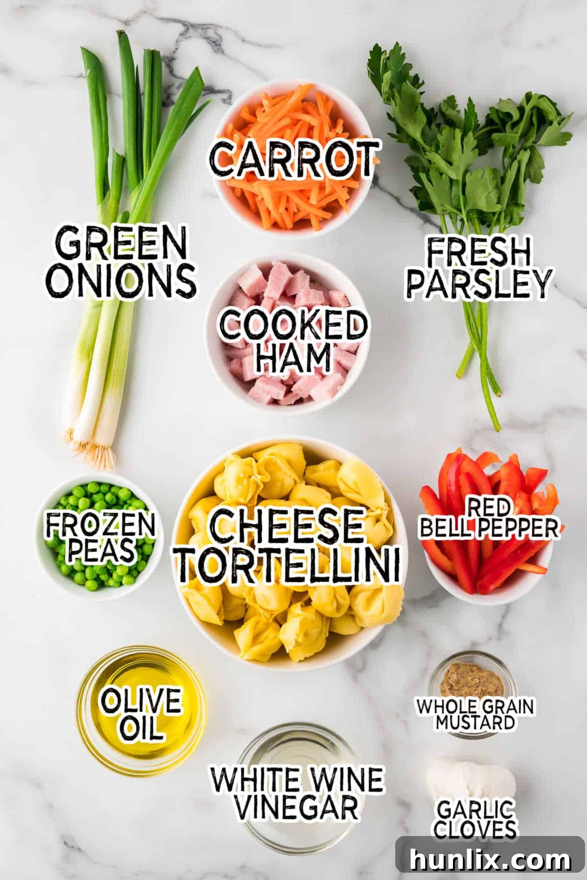 A selection of fresh ingredients laid out on a wooden surface, ready to be combined for tortellini salad.