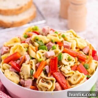 Tortellini salad in a white bowl.