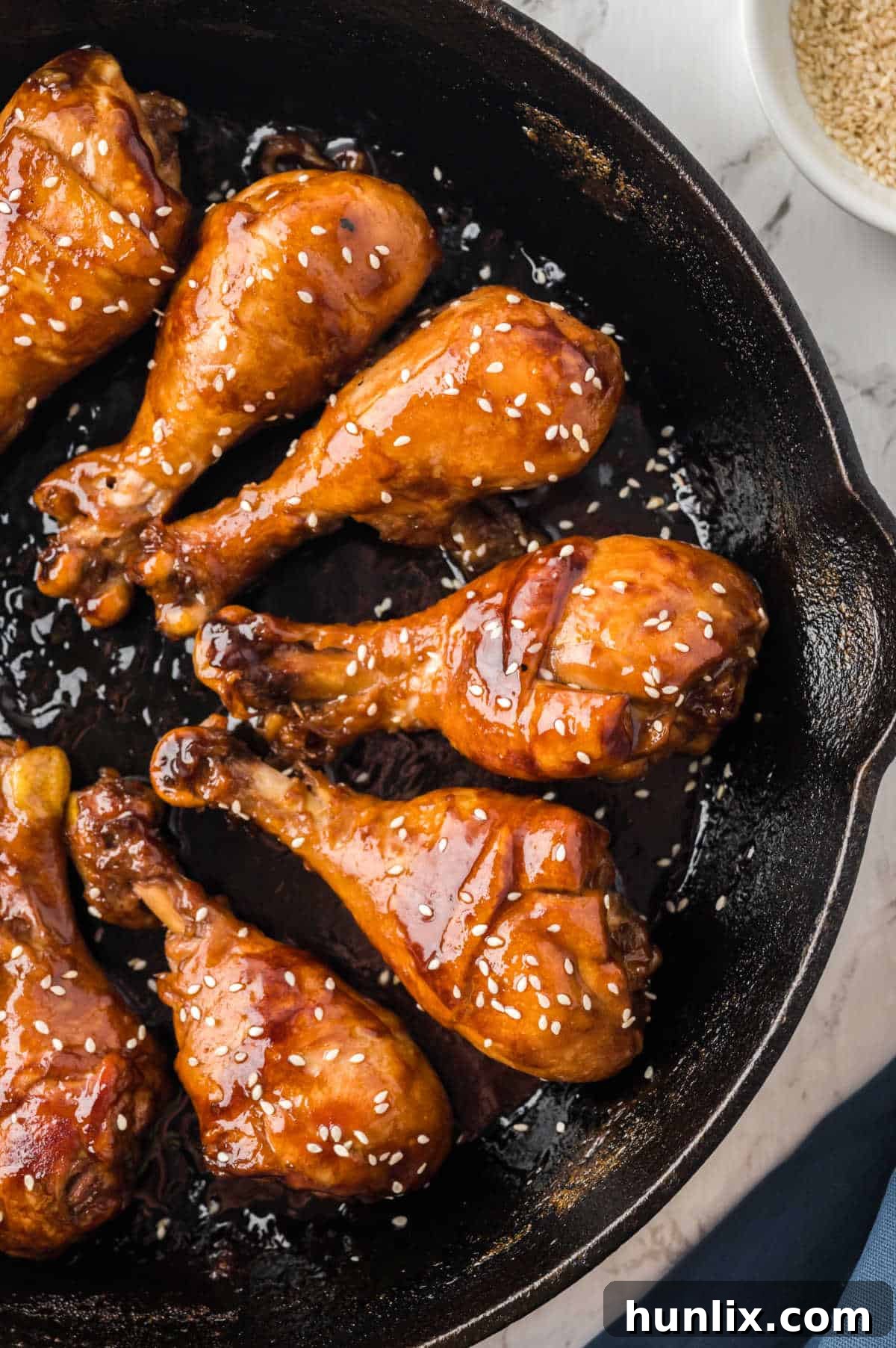 The finished sticky chicken dish displayed in a cast iron skillet, garnished with sesame seeds.
