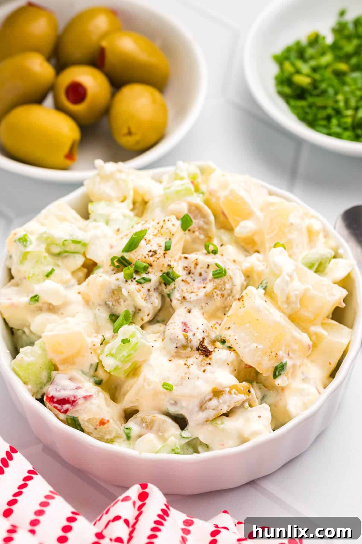 A close-up of a serving of cheese potato salad, highlighting its rich, creamy texture and vibrant ingredients.