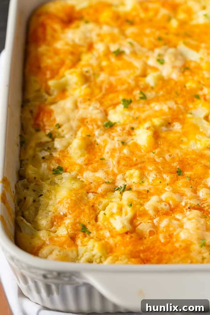 A golden-brown, bubbling cauliflower bake topped with melted cheese, fresh parsley, and a crispy crust, served in a rustic casserole dish.