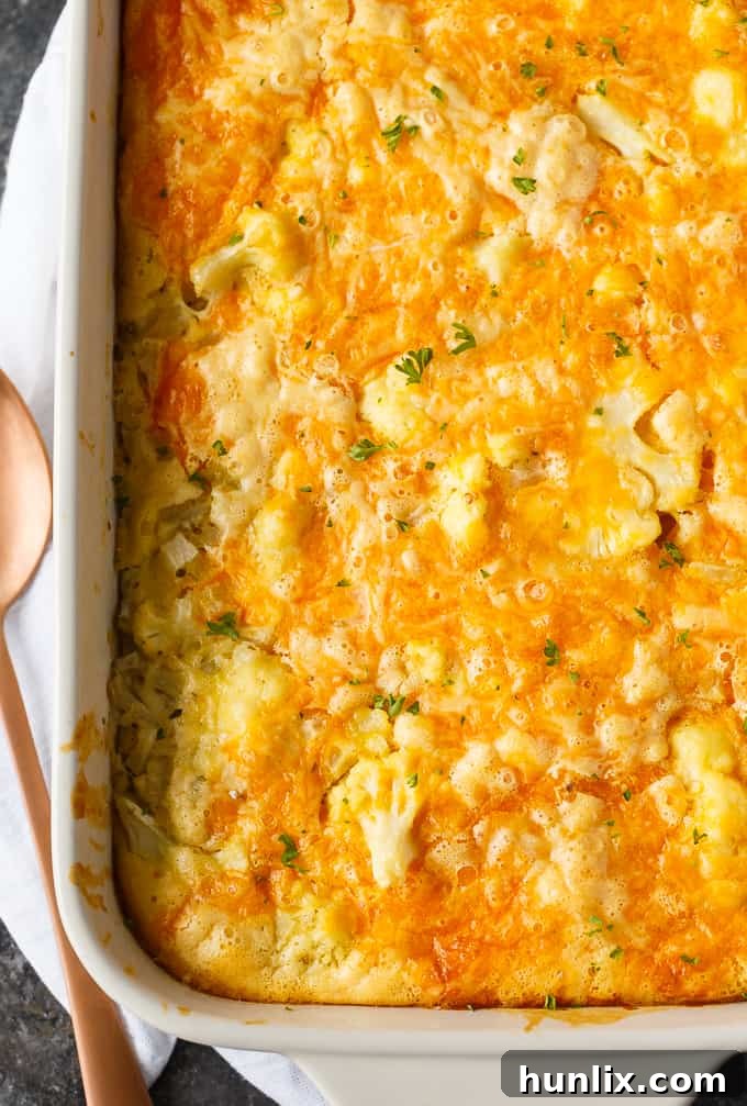 Close-up of a serving of cheesy cauliflower bake, showing the creamy texture, golden crust, and tender cauliflower florets.