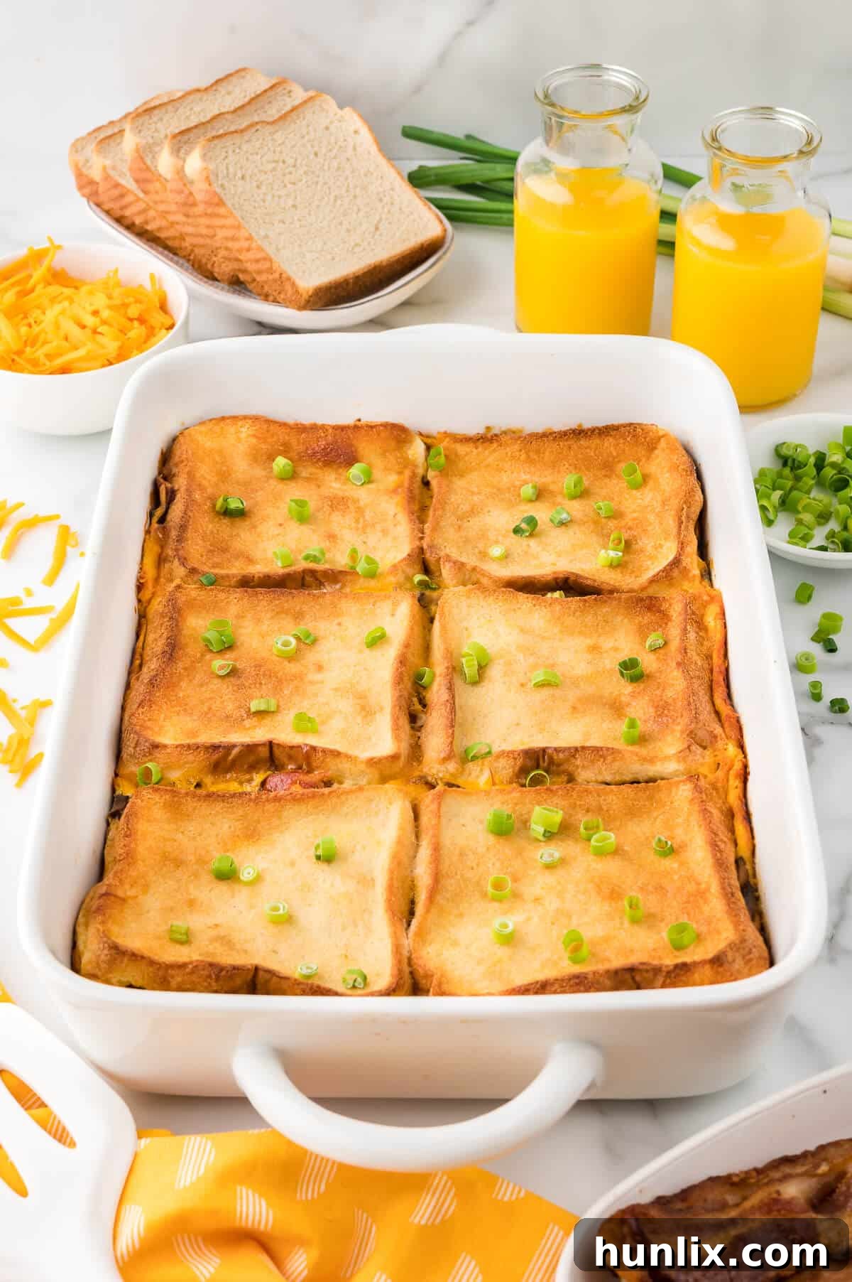 A golden-brown bacon breakfast casserole, freshly baked in a rectangular pan, with crispy bacon bits and melted cheese visible on top.