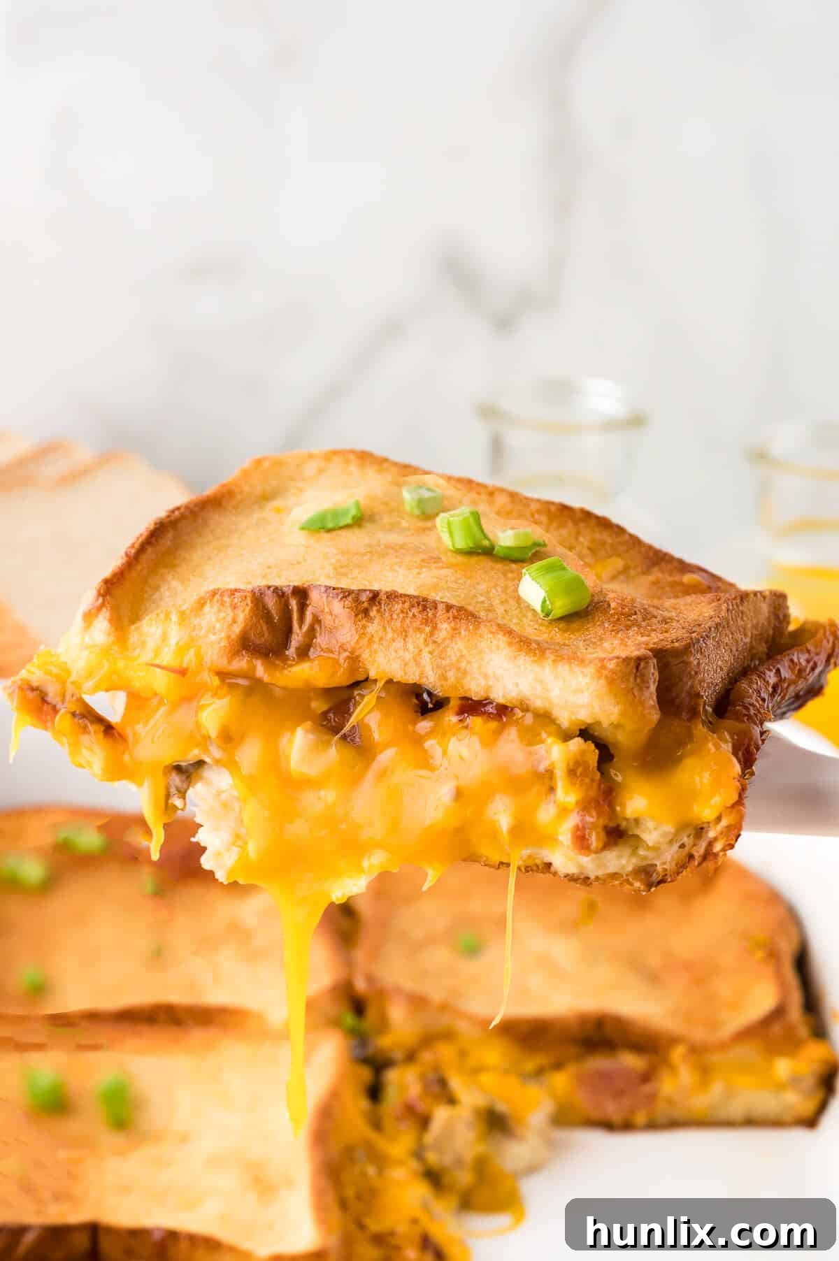 A serving of bacon breakfast casserole being lifted from a pan with a serving spatula, showcasing its golden-brown top and layered interior.