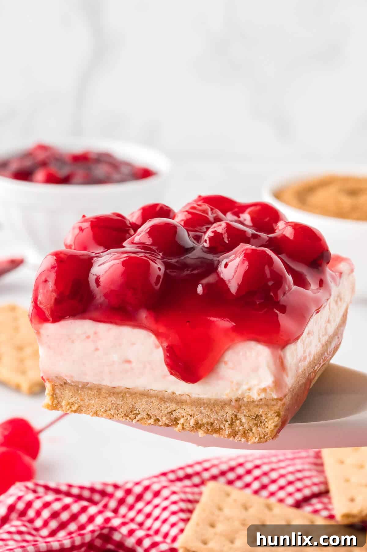 A slice of cherry cheesecake on a serving spoon, showcasing its layers.