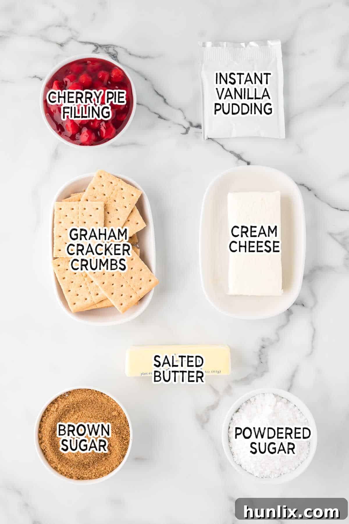 Ingredients for no-bake cherry cheesecake laid out on a marble counter.