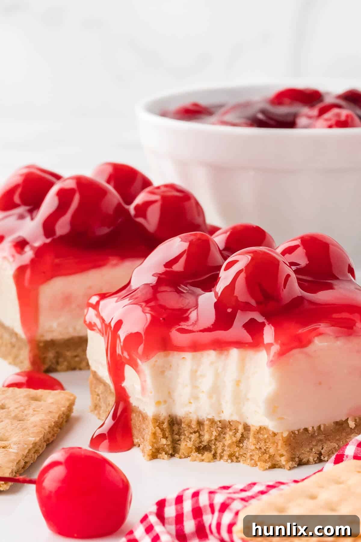 A slice of cherry cheesecake with a small bite taken out, resting on a white plate.