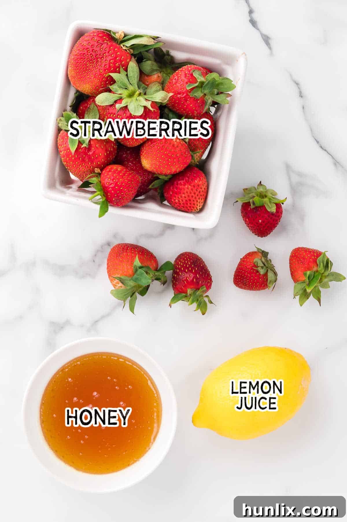Fresh strawberries, a jar of honey, and a sliced lemon, the simple ingredients for homemade strawberry sauce.