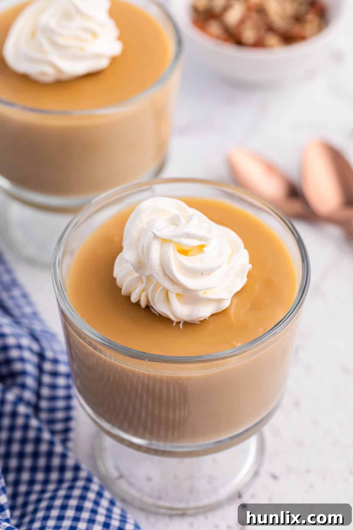 Silky Butterscotch Indulgence 2 A serving of luxurious homemade butterscotch pudding, topped generously with fluffy whipped cream, presented in an elegant parfait dish.