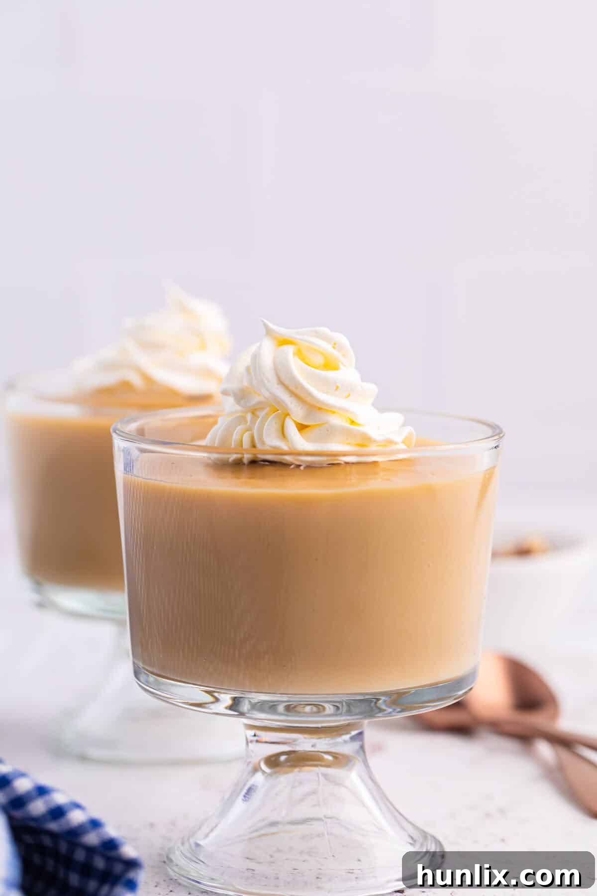 Silky Butterscotch Indulgence 9 A collection of elegant parfait dishes filled with perfectly set butterscotch pudding, generously topped with freshly whipped cream, ready for serving.