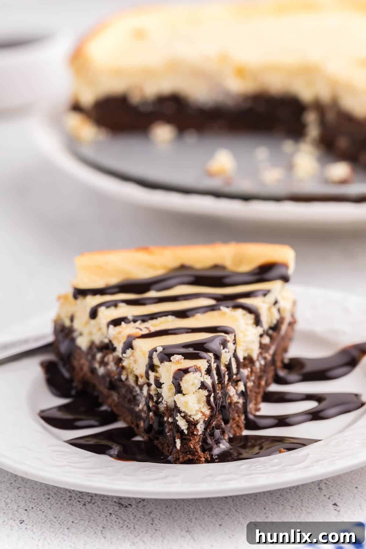 A perfectly sliced brownie bottom cheesecake on a white plate, showcasing its distinct layers.