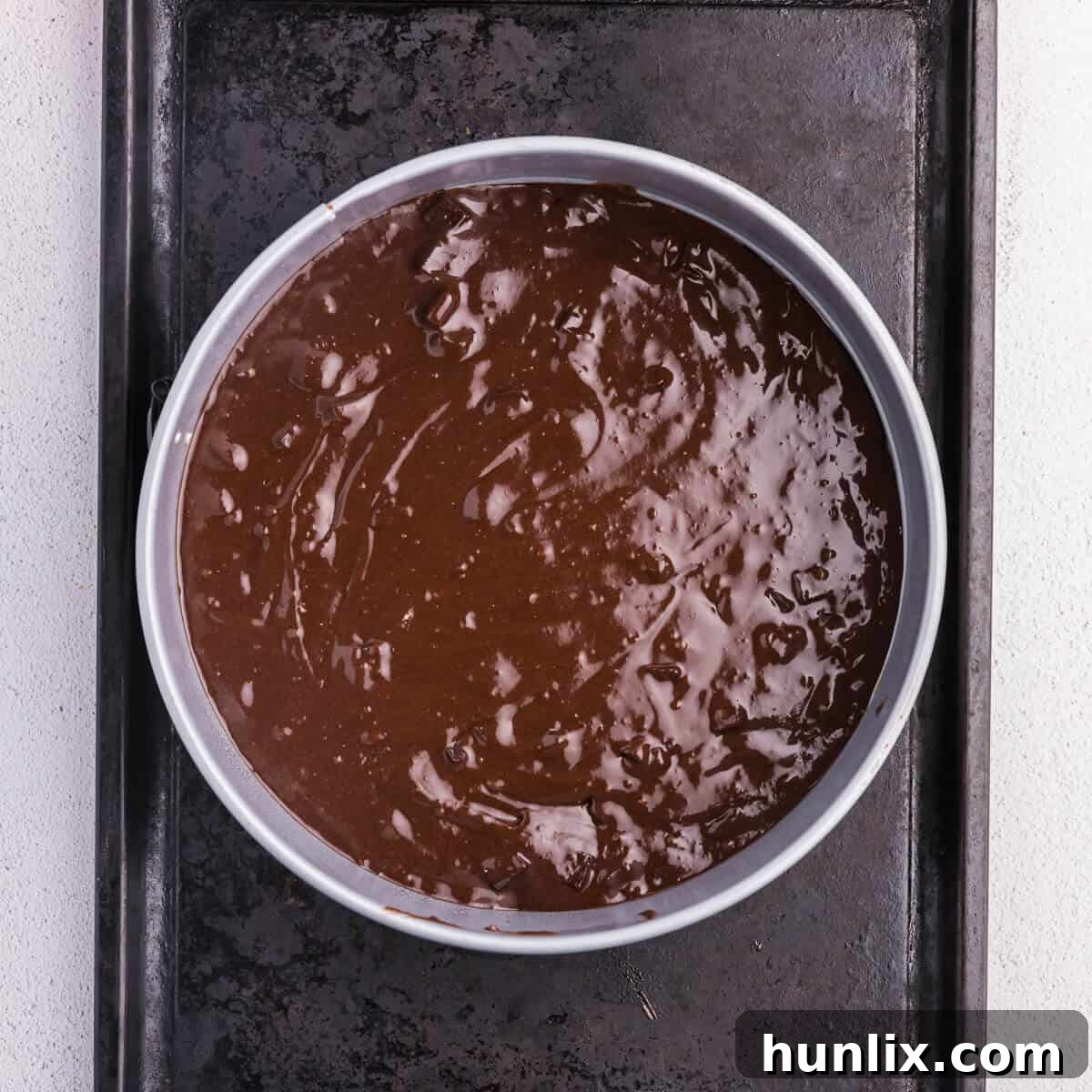 Brownie batter spread evenly into a 9-inch springform pan, ready for its initial bake.