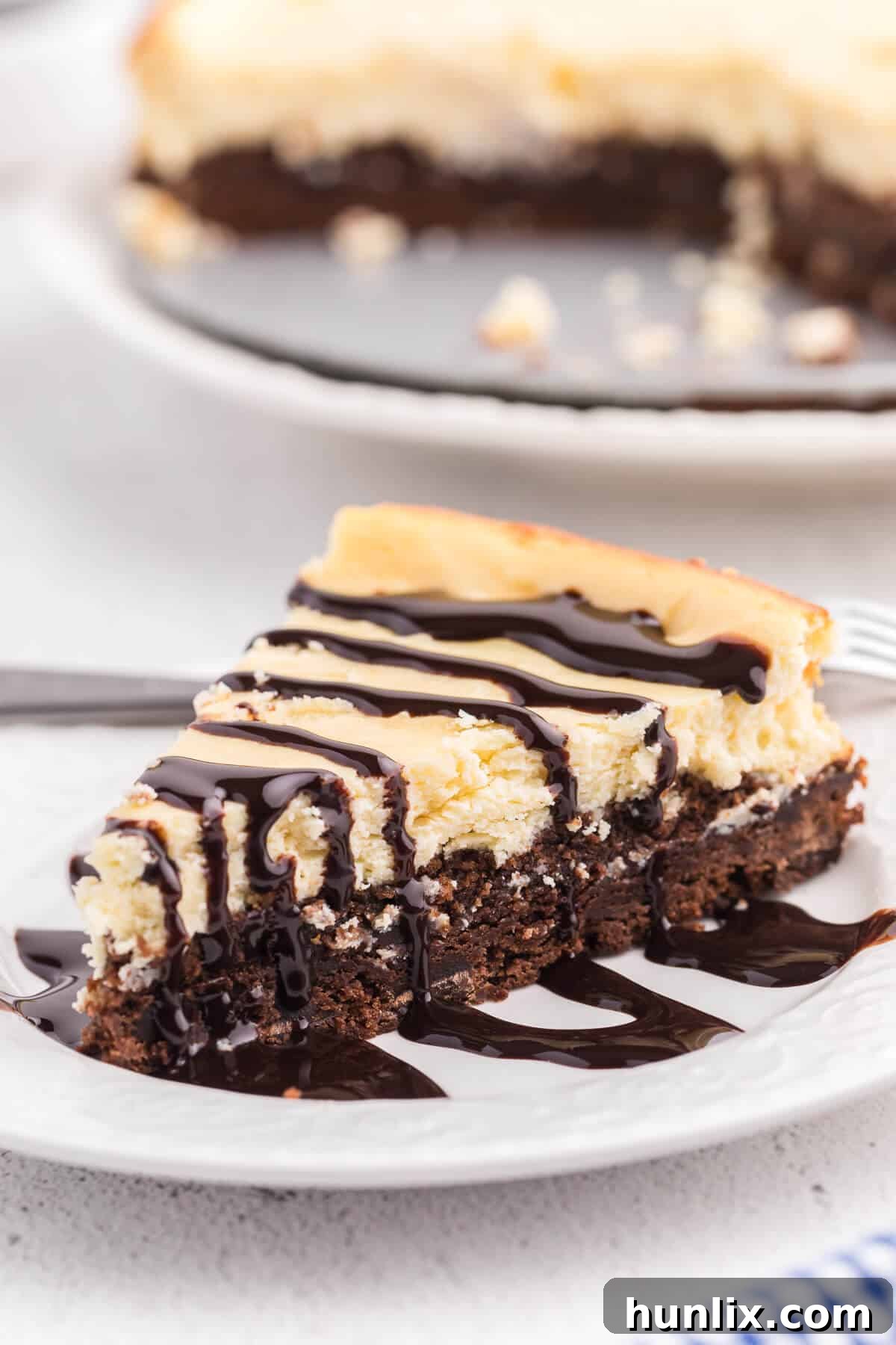 A slice of brownie bottom cheesecake on a plate with a bite taken, showing the delicious layers.