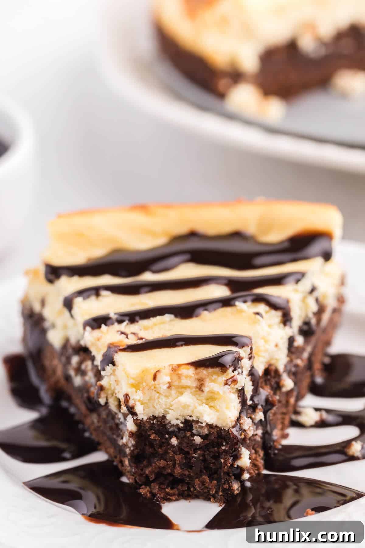 A delectable slice of brownie bottom cheesecake, slightly angled, with a small bite missing, tempting viewers.