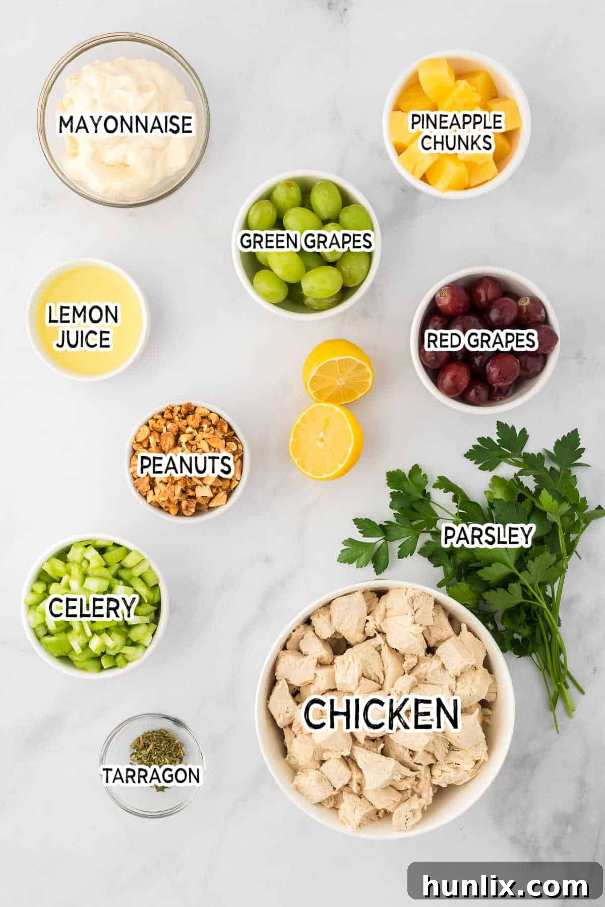 A beautiful spread of fresh ingredients laid out for making chicken salad with grapes, including chicken, grapes, celery, pineapple, and peanuts.