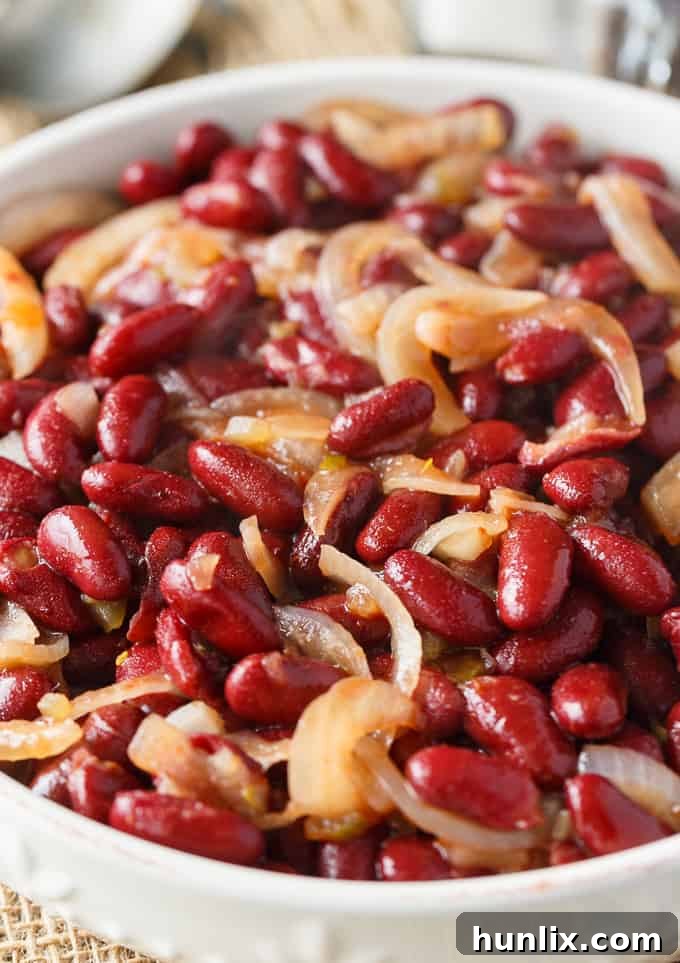Oven-Baked Kidney Bean Delight 3 A close-up of the kidney bean bake being scooped from the casserole dish, showing the vibrant red beans, tender onions, and glossy sauce.