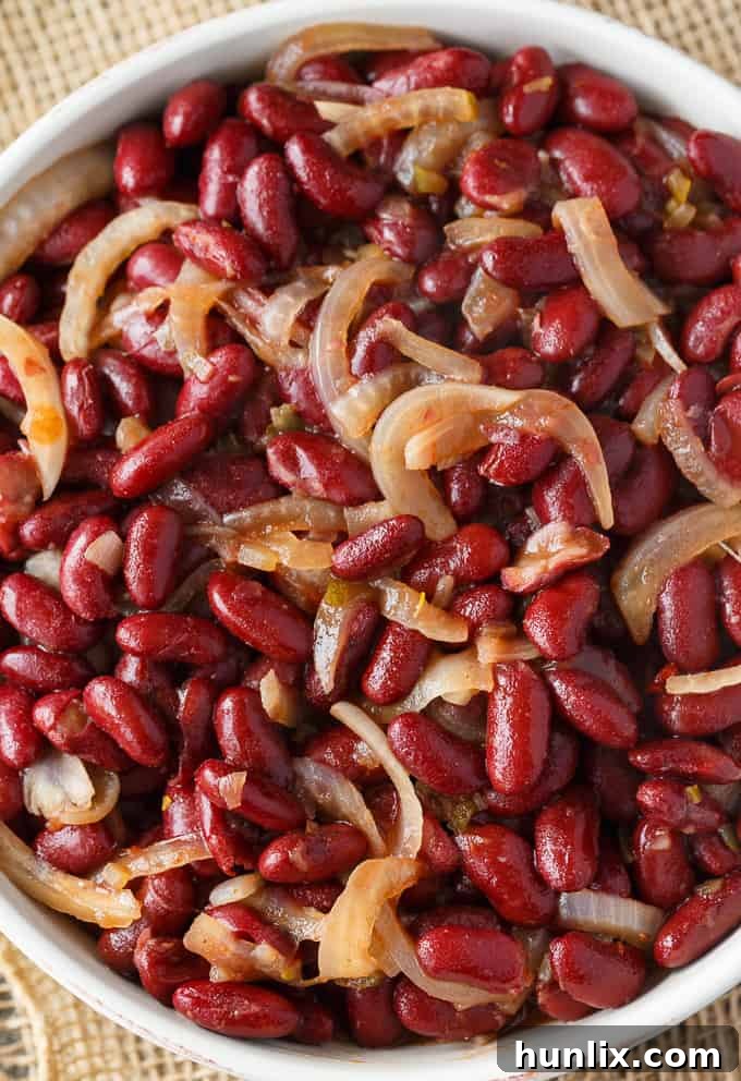 Oven-Baked Kidney Bean Delight 4 A bowl filled with the uncooked mixture of kidney beans, chili sauce, relish, and sliced onions, ready to be transferred to a casserole dish.