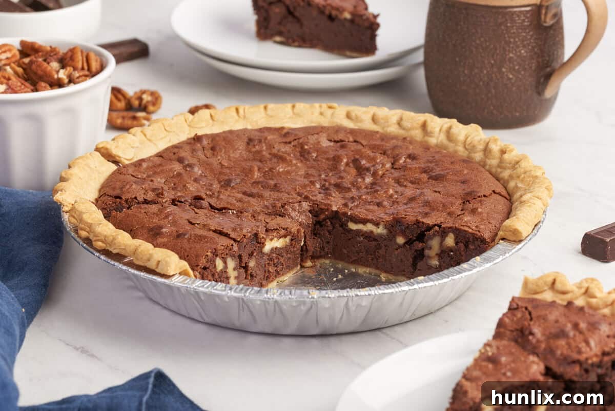 Decadent Chocolate Pecan Pie 7 A whole chocolate pecan pie with a few slices already removed, showing the rich texture inside.