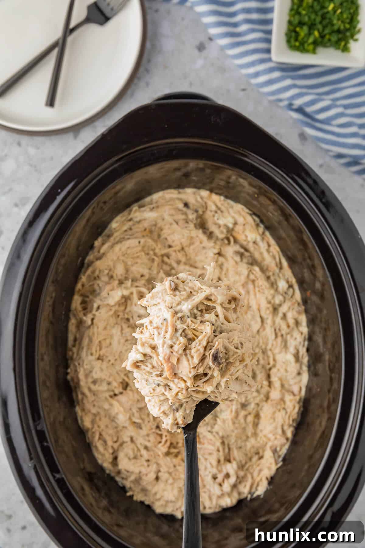 Dreamy Slow Cooker Cream Cheese Chicken 2 Slow cooker cream cheese chicken in a crockpot with a serving spoon.