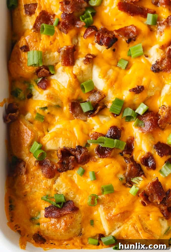 Individual serving of Bacon and Egg Biscuit Casserole on a plate, garnished with green onions.