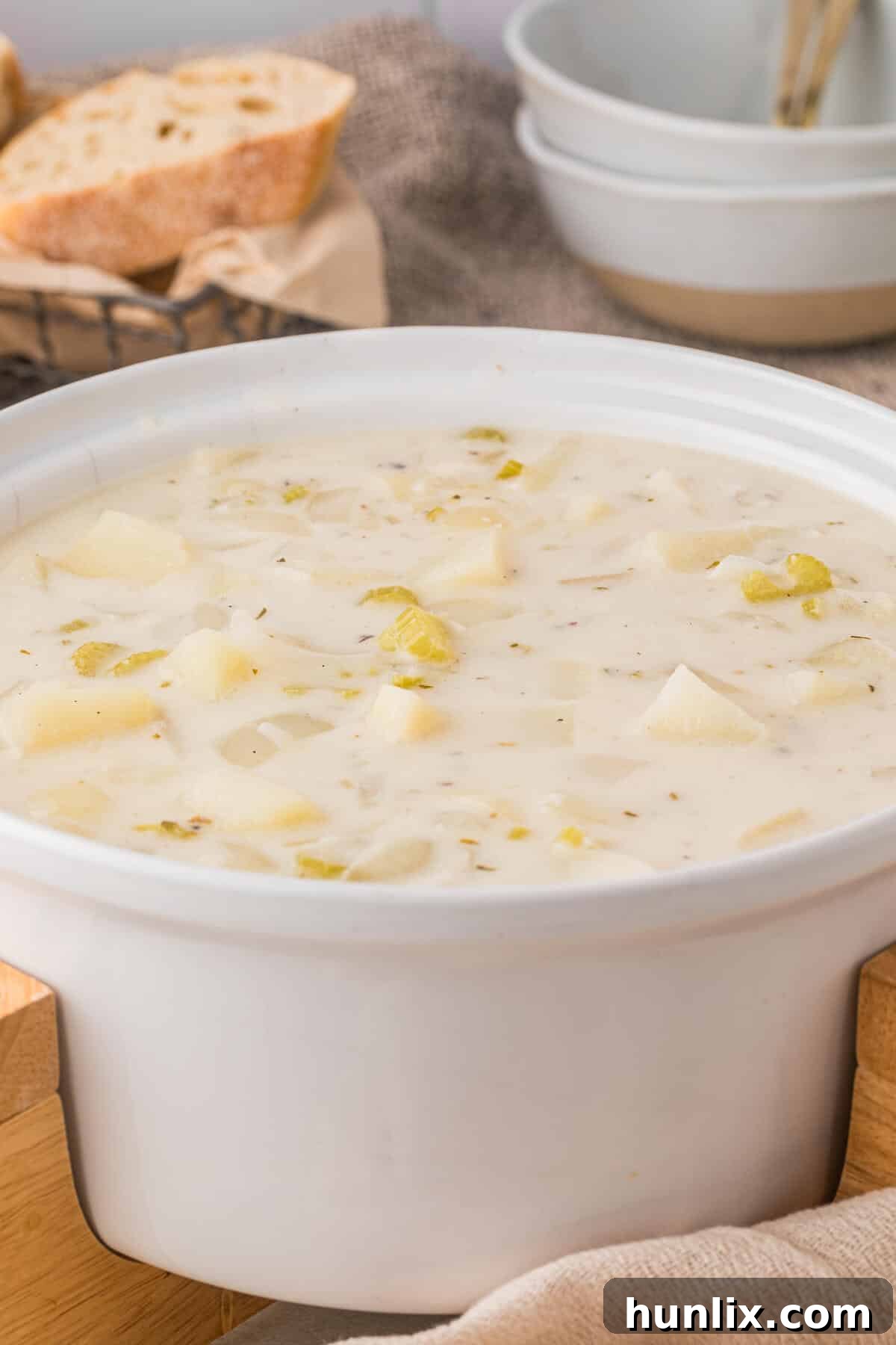 A white pot of German potato soup, showcasing its thick and creamy texture.